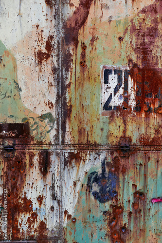 Rusty abstract wall. Background with cracks and green paint. Orange green vintage metal wall with number © Tengyart