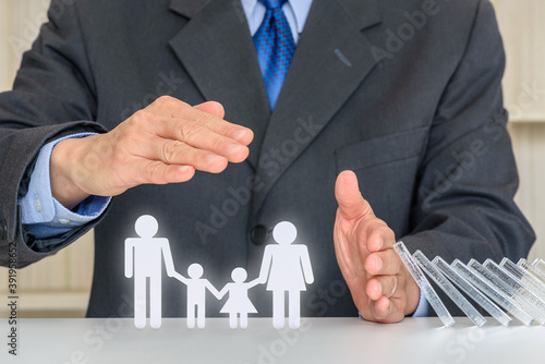 Businessman uses hands and an umbrella to protect family members e.g parents and two child