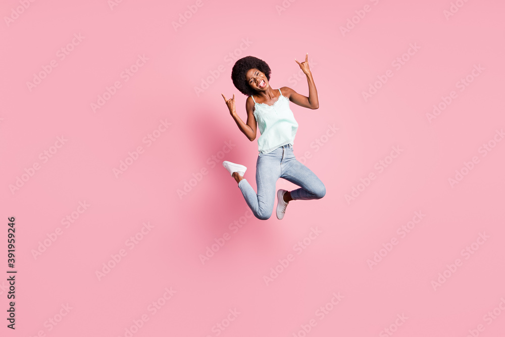 Full body photo of attractive carefree lady jump show fingers sign jeans sneakers tank-top isolated on pink color background
