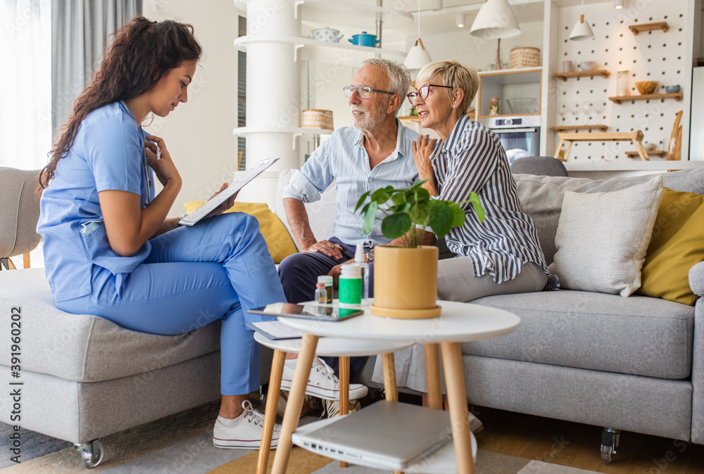 Female nurse talking to seniors patients while being in a home visit, senior couple signs an insurance policy. Female nurse talking to seniors patients while being in a home visit, senior couple signs an insurance policy.