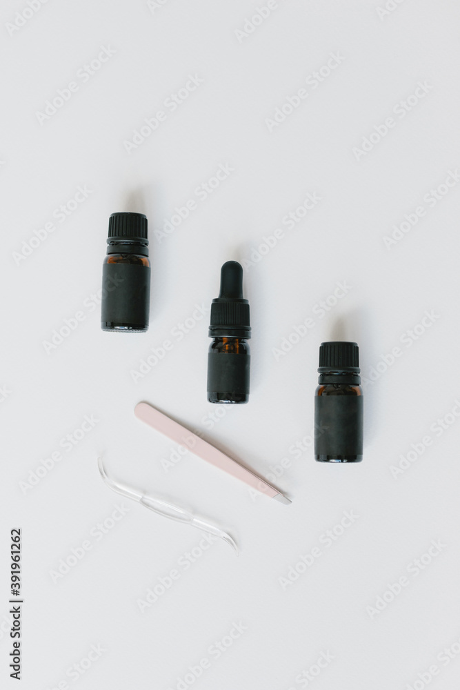 Three bottles, tweezers and a brush on a light background. The concept of eyebrow coloring, brow master, brow bar. Three bottles, tweezers and a brush on a light background. The concept of eyebrow coloring, brow master, brow bar.