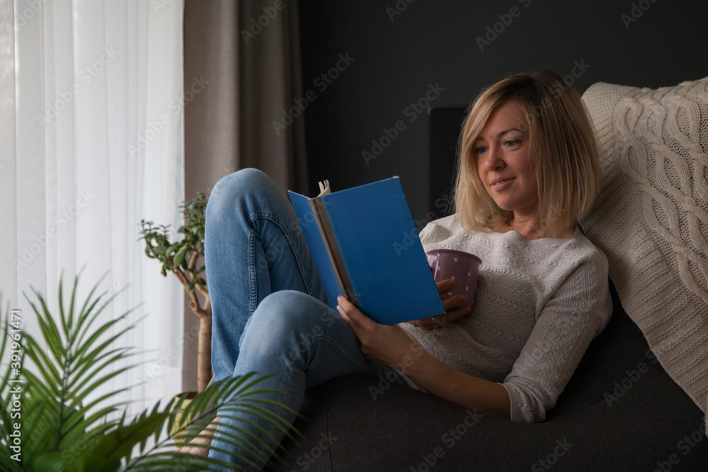Relaxing woman reading a book and drinking tea at home Relaxing woman reading a book and drinking tea at home