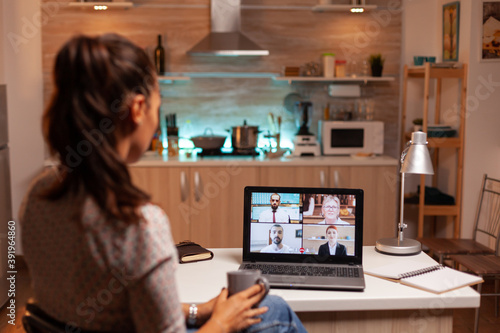 Businesswoman having a video conference with team during midnight using laptop in home kitchen. Corporate meeting using modern technology, laptop late at night , tech, agency, advisor, work