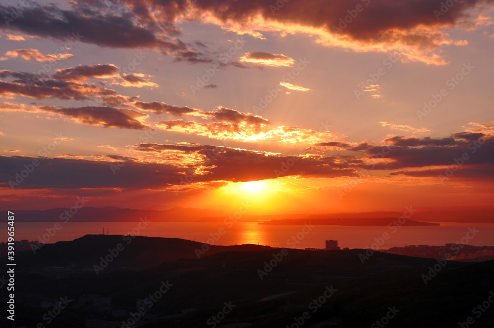 Sunset over the sea and beautiful cloudscape. Japanese sea, Vladivostok city, Primorsky Krai, Russia.