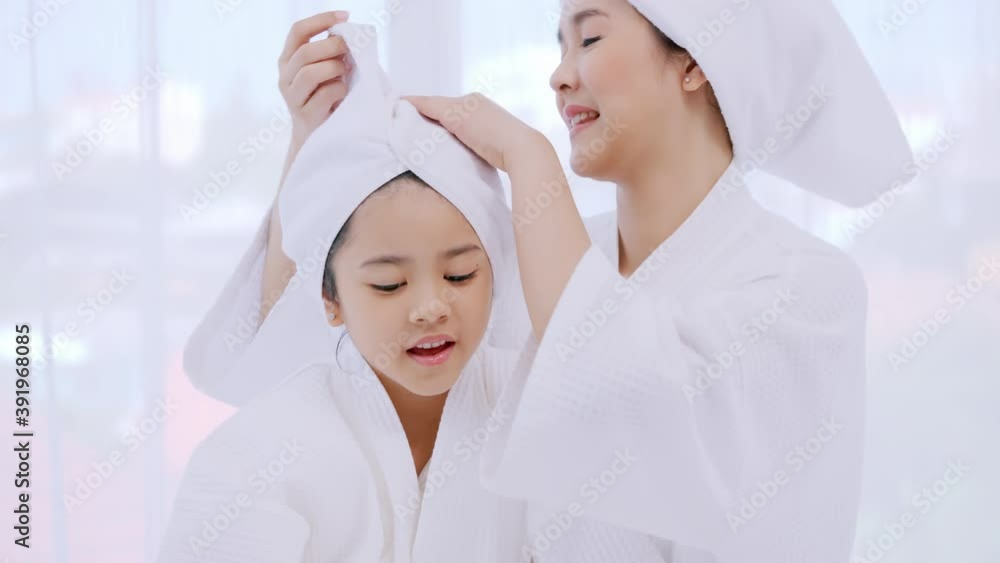 Mother with little daughter in bathrobes doing beauty treatment together in bedroom. Mother with little daughter in bathrobes doing beauty treatment together in bedroom.