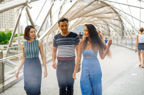 Three happy young asian friends outdoor standing and walking along city bridge © jovannig