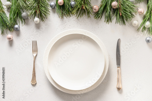 Christmas table setting with white holiday elegant decorations on white table. View from above.