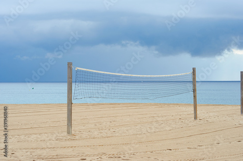 Tennis net on the beach on a cloudy day. No people.