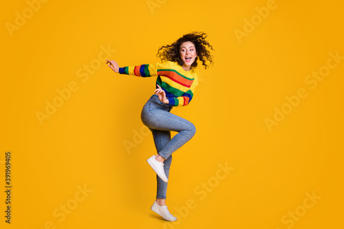 Full length photo of funny jumping woman dressed casual colorful sweatshirt dancing looking empty space isolated yellow color background