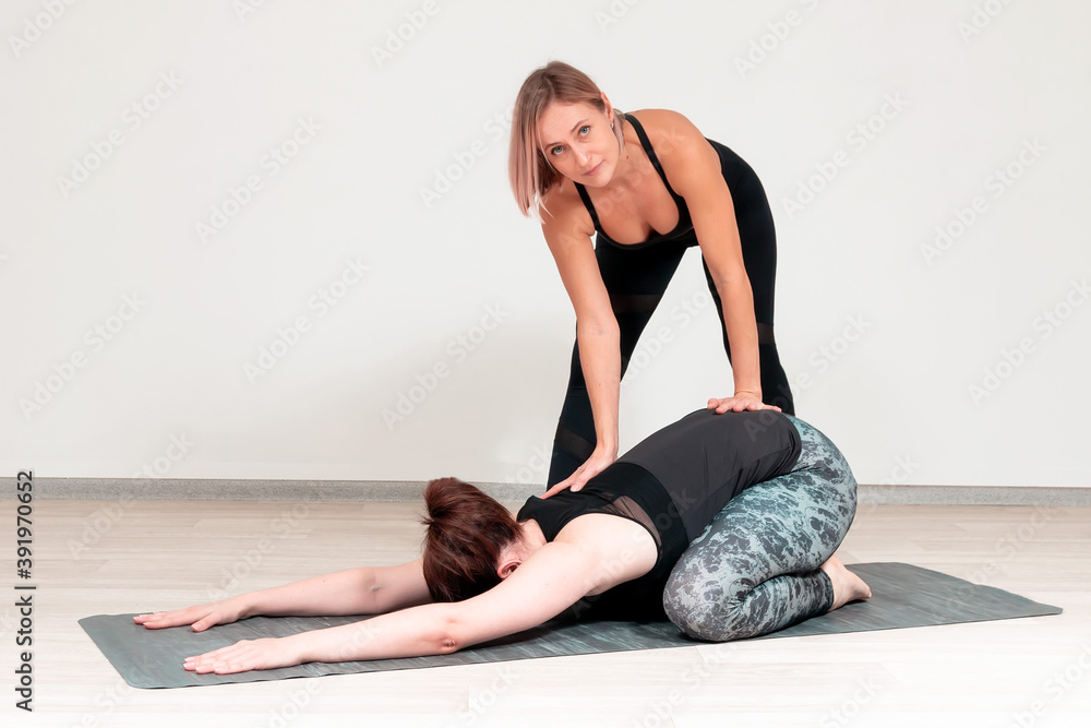 Woman trainer helps to perform yoga exercises Woman trainer helps to perform yoga exercises