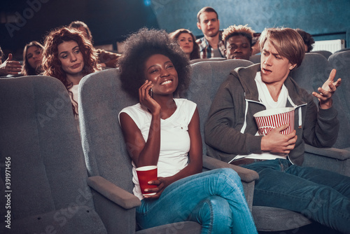 Woman smiling and talking on the phone in cinema.