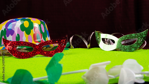 Brazilian carnival masks and props arranged on green surface, red background, selective focus.