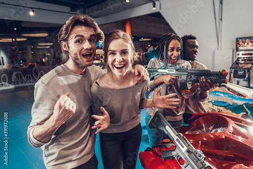 Group of young friends posing with guns in arcade.