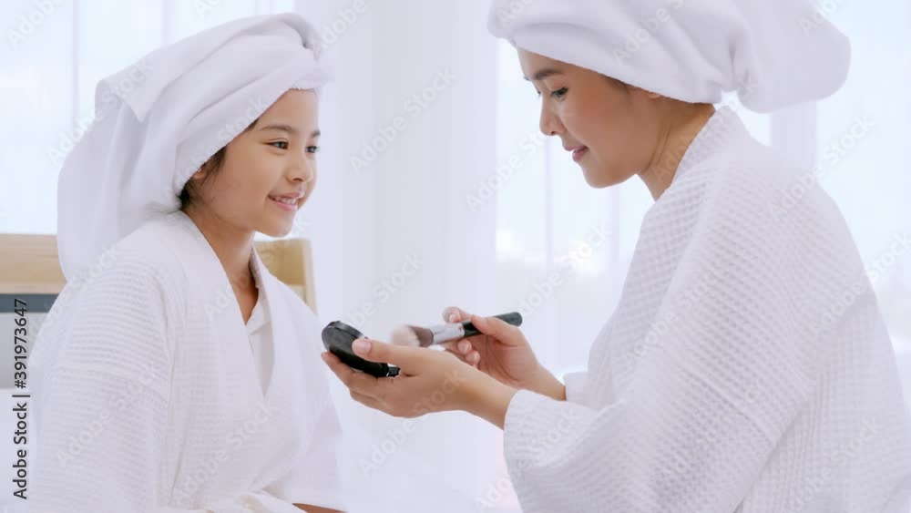 Mother with little daughter in bathrobes doing beauty treatment together in bedroom. Mother with little daughter in bathrobes doing beauty treatment together in bedroom.