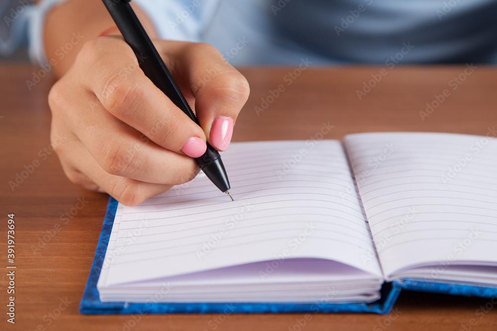 Woman writes in her notebook. Wooden table. Woman writes in her notebook. Wooden table.