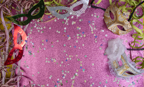 Brazilian carnival masks and props arranged on a shiny pink surface, top view. photo