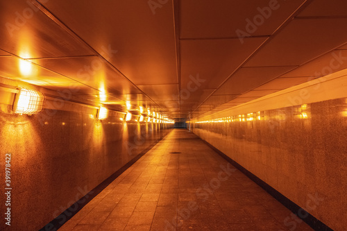 Empty underground passage illuminated with yellow light.
