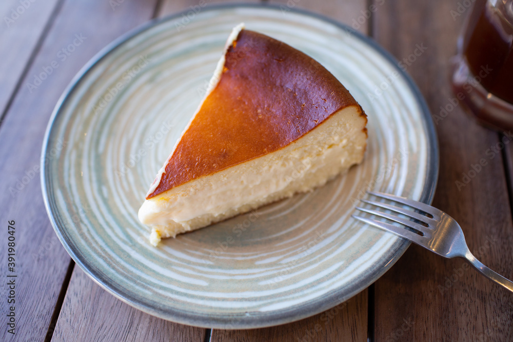 Fototapeta premium Cheescake San Sebastian slice on dish at cafe table