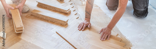 zwei Handwerker verlegen einen wunderschönen klassischen Holzboden auf einer Baustelle