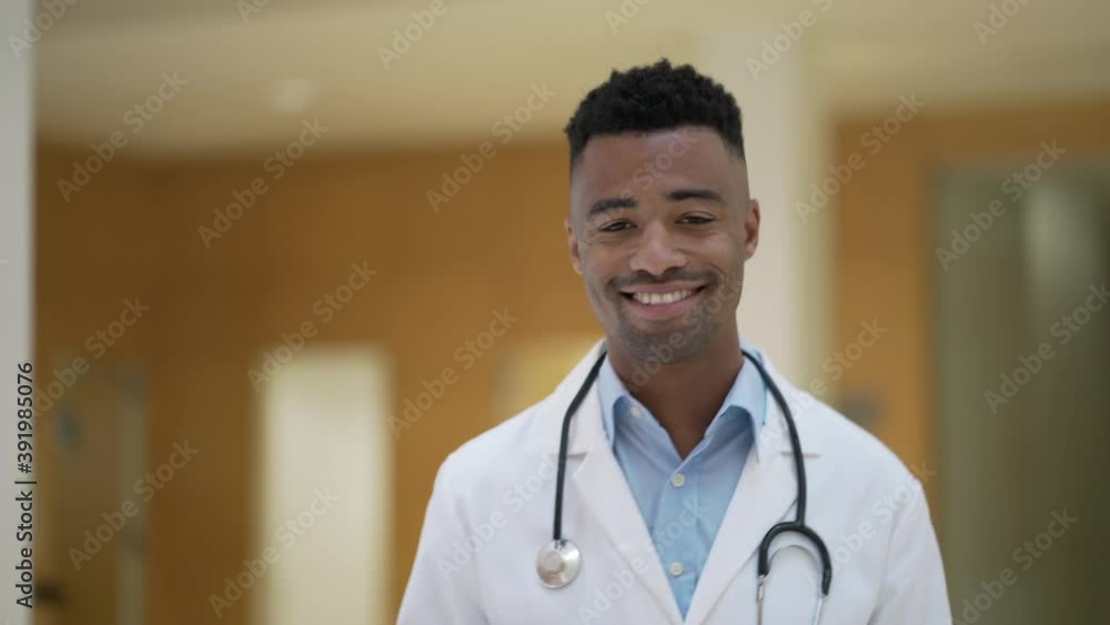 Portrait of smiling doctor sitting at desk, looking at camera Portrait of smiling doctor sitting at desk, looking at camera