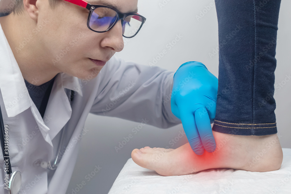 An orthopedic surgeon examines a woman's leg. Foot pain, tendon sprains