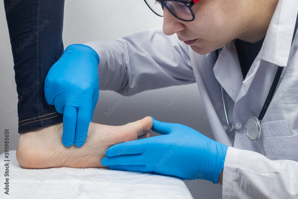 An orthopedic surgeon examines a woman's leg. Foot pain, tendon sprains