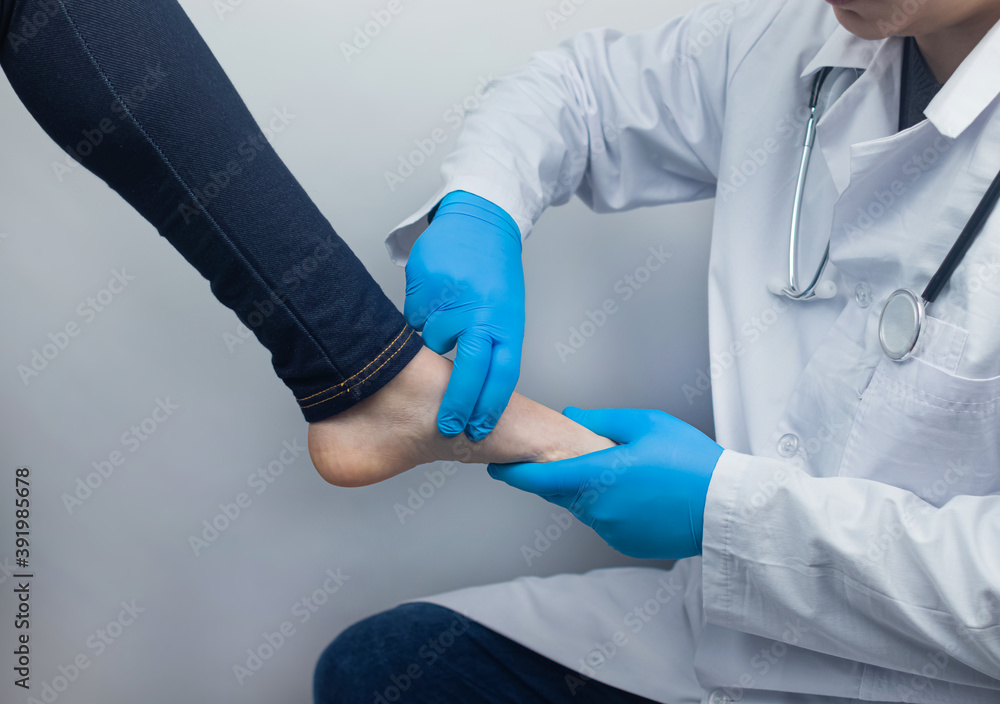An orthopedic surgeon examines a woman's leg. Foot pain, tendon sprains