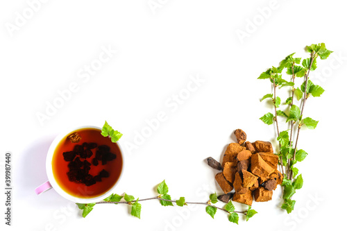 Cup of tea of birch chaga mushroom and crushed chaga fungus pieces for tea brewing isolated on a white background. space for text photo