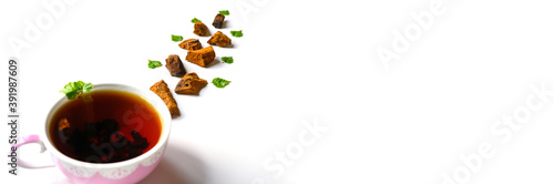 Cup of tea of birch chaga mushroom and crushed chaga fungus pieces for tea brewing isolated on a white background. banner. space for text photo