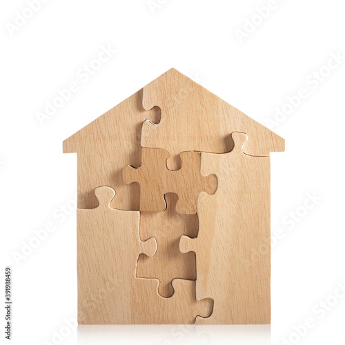 House built out of puzzle pieces on wooden background photo