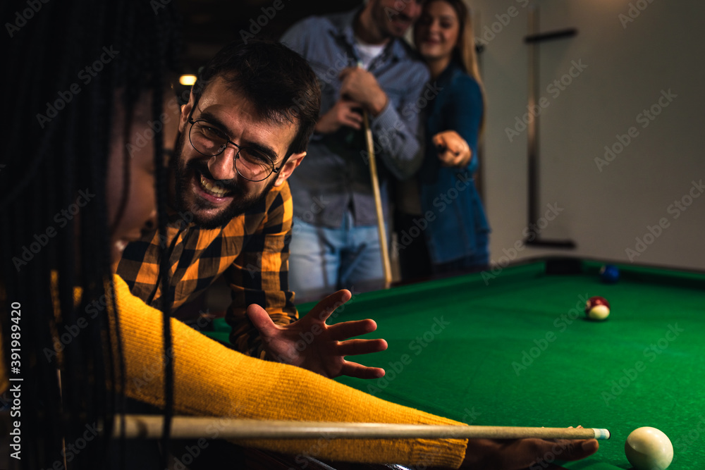 Group of friends having fun in bar playing billiard together.