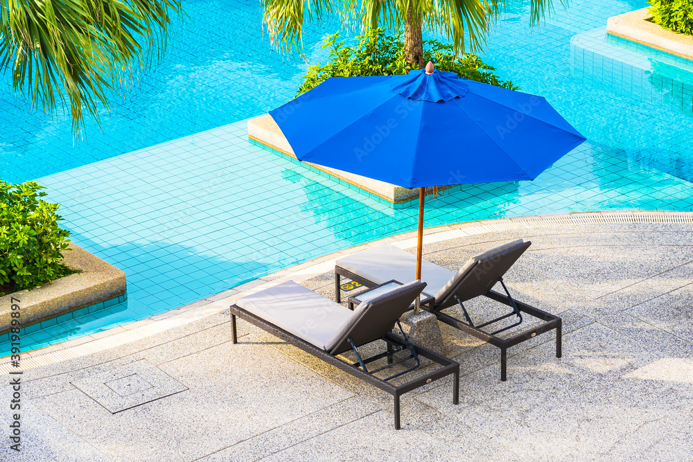 Beautiful empty chair with umbrella around outdoor swimming pool