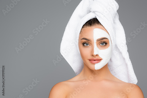 woman with towel on head and clay mask on face isolated on grey