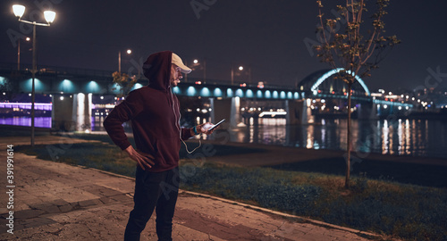 Athletic sporty man training in hoodie sweatshirt in urban city park.