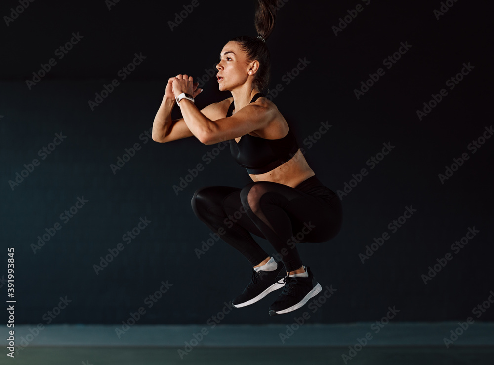 Sports woman jumping in gym. Muscular fit woman exercising indoors.