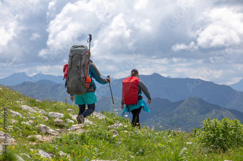 Tourists with backpacks walk the trail along the mountain route