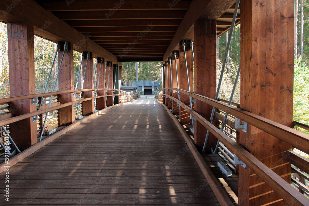 Pedestrian trail covered with roof. Wooden bridge construction. Bridge with railings. Pedestrian trail covered with roof. Wooden bridge construction. Bridge with railings.