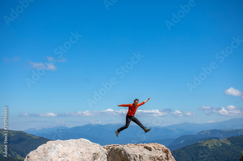 Young man jumping for joy on the top of the mountain