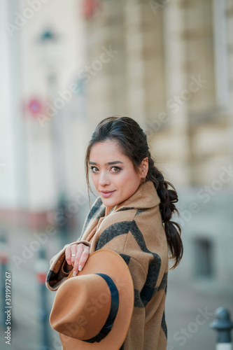 Beautiful young woman in a hat with coffee walks in a european city