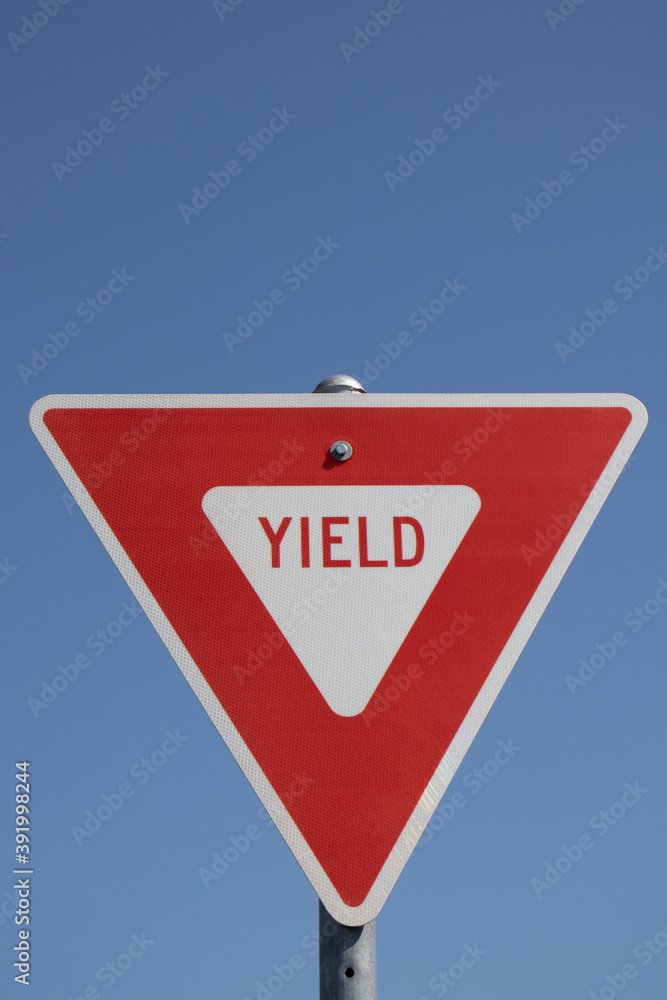 Red and white triangular yield sign against blue sky Red and white triangular yield sign against blue sky