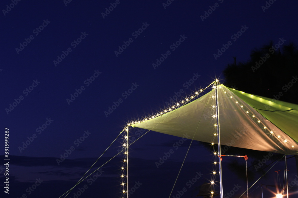 Green roof tent lit at night with blue sky background