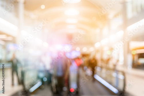 Blurred background with bokeh light in empty airport due to coronavirus covid new normal rule shop store area runway escalator with travel passenger fly flight travel walking in hallway in terminal