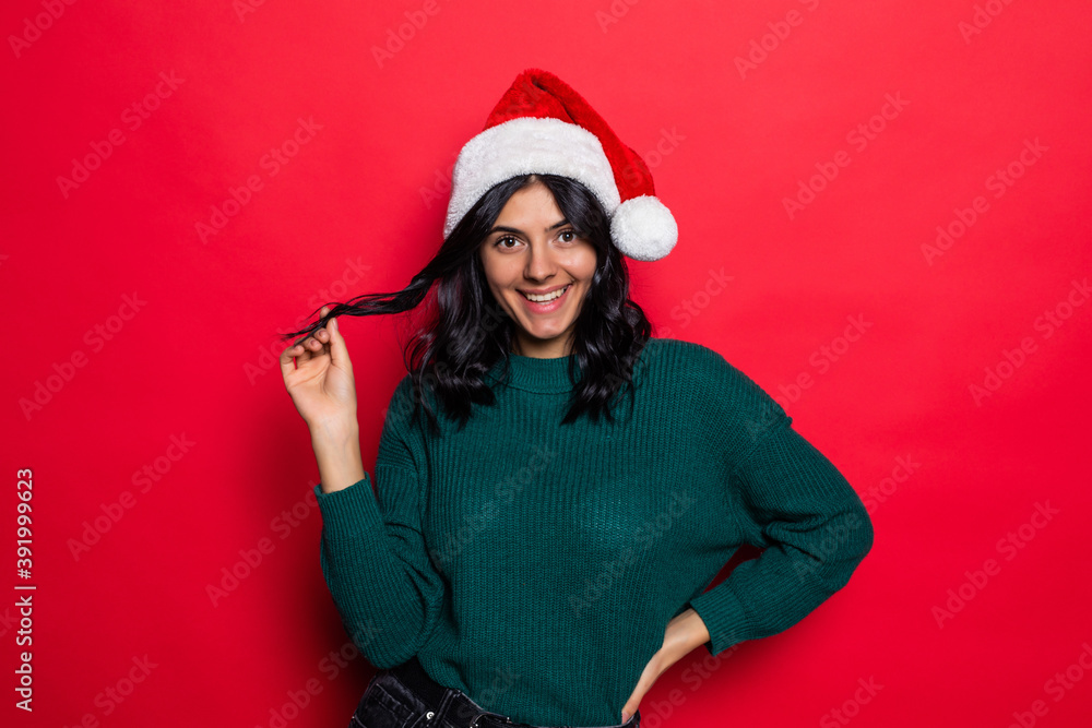 Young woman wearing santa hat have fun isolated on red background