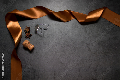 A dark background with gold ribbon, spice cork champagne and muzlet with room for your text. The concept of selling alcoholic beverages at a discount. photo