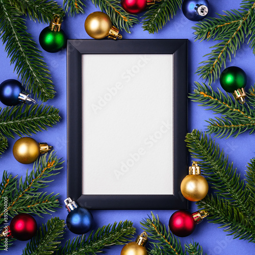 Christmas composition with empty picture frame. Colorful ornament and fir branches decorations. Mock up greetings card template