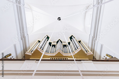 vault of a bright church with pipes from the organ, geometric photograph of the church ceiling