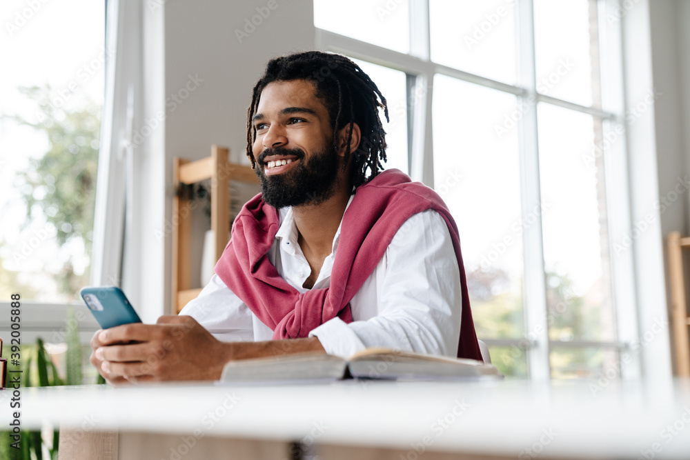 Happy african american guy smiling and using cellphone Happy african american guy smiling and using cellphone