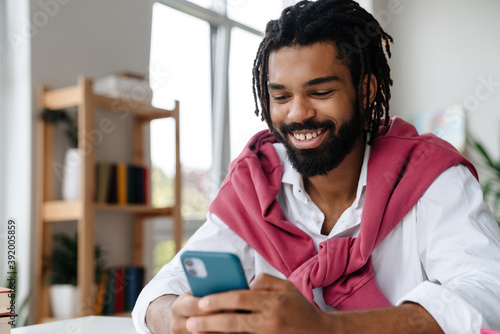 Happy african american guy smiling and using cellphone