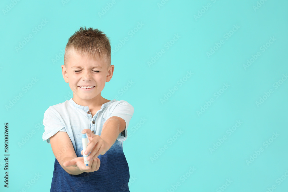 Scared diabetic boy taking blood sample on color background Scared diabetic boy taking blood sample on color background