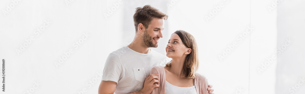 happy man and woman looking at each other while hugging at home, banner happy man and woman looking at each other while hugging at home, banner